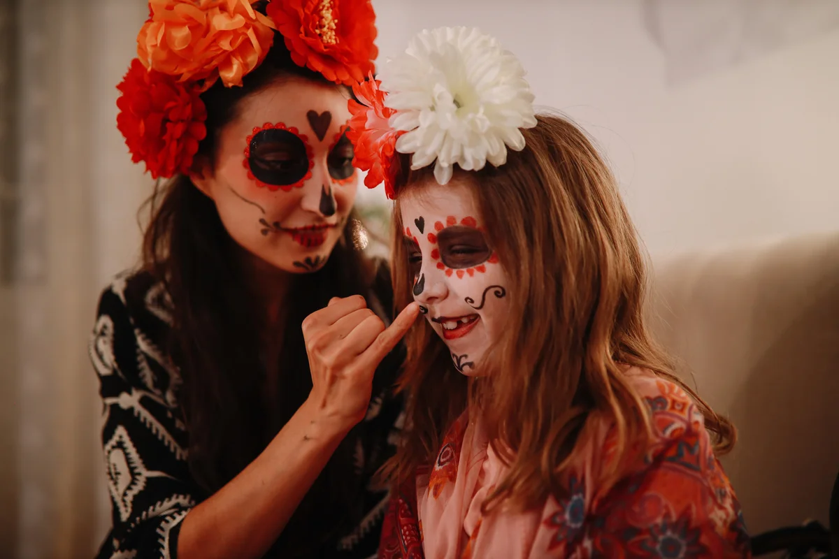 Mon putting white makeup on daughter's face for Day of the Dead costume.