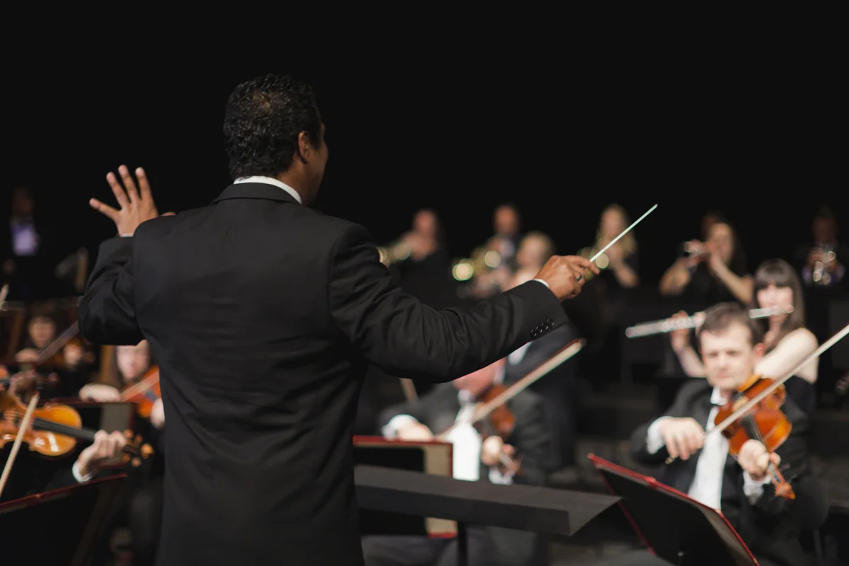 Conductor with baton leading orchestra