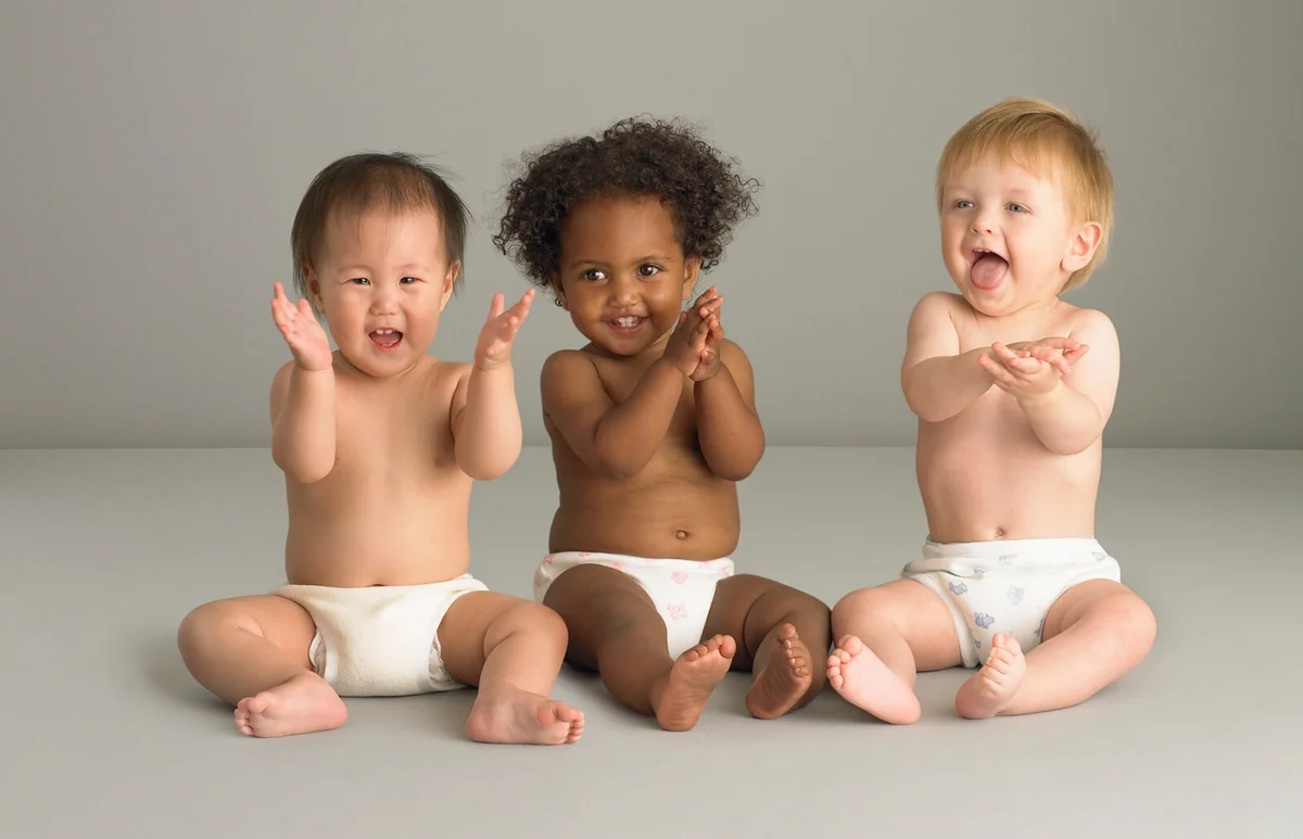 Baby girl sitting between two baby boys