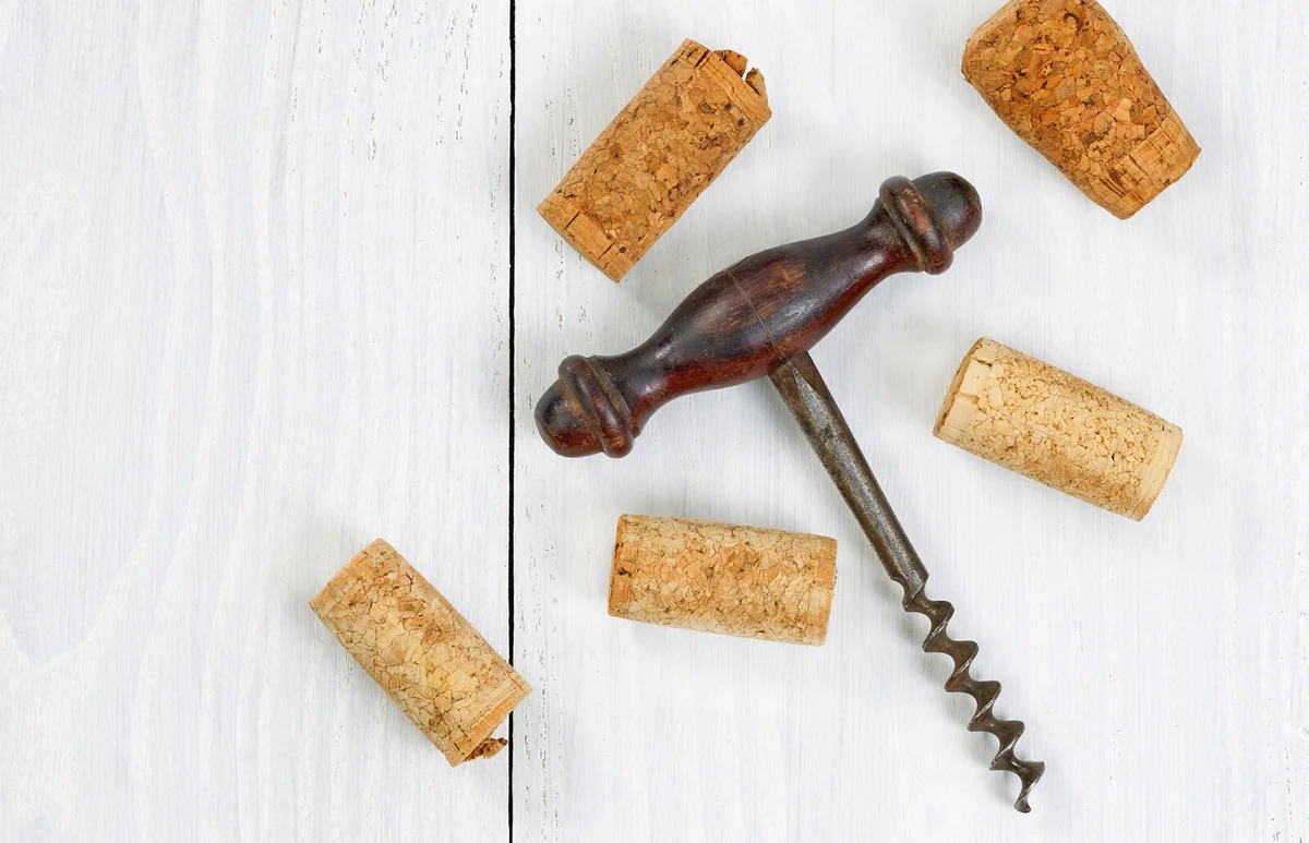 Vintage corkscrew with old corks on white wooden boards