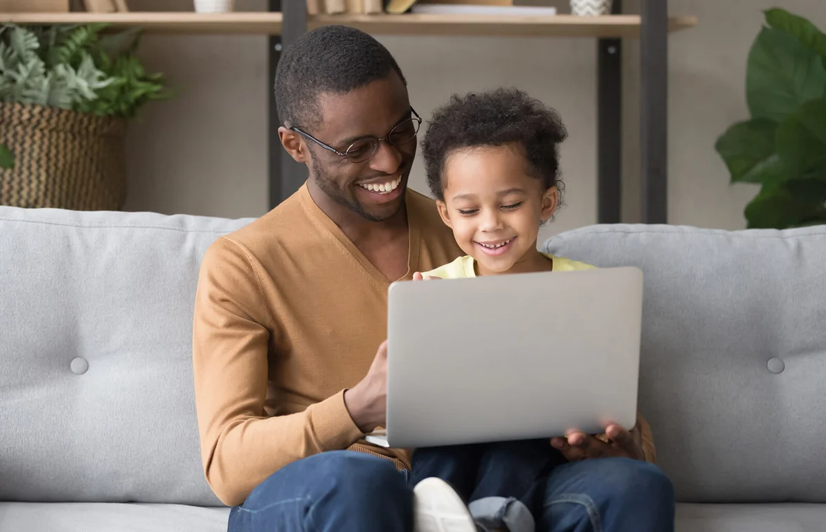 Smiling dad and little son play computer game