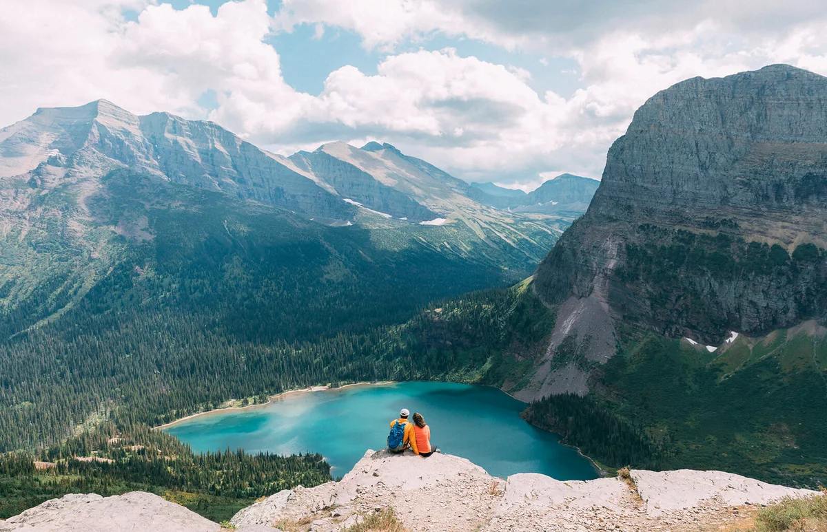 Couple sitting on cliff, Glacier National Park, Montana, USA
