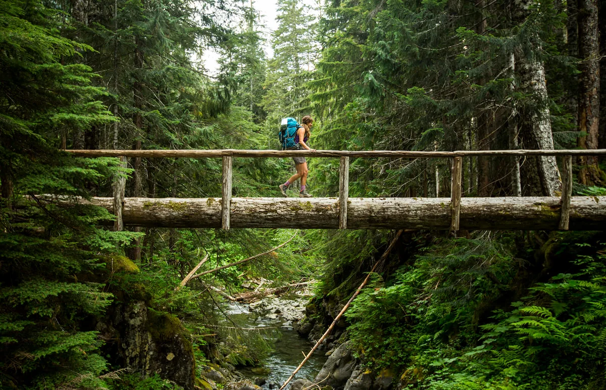 A female backpacking along a trail in the Olympic National Park.