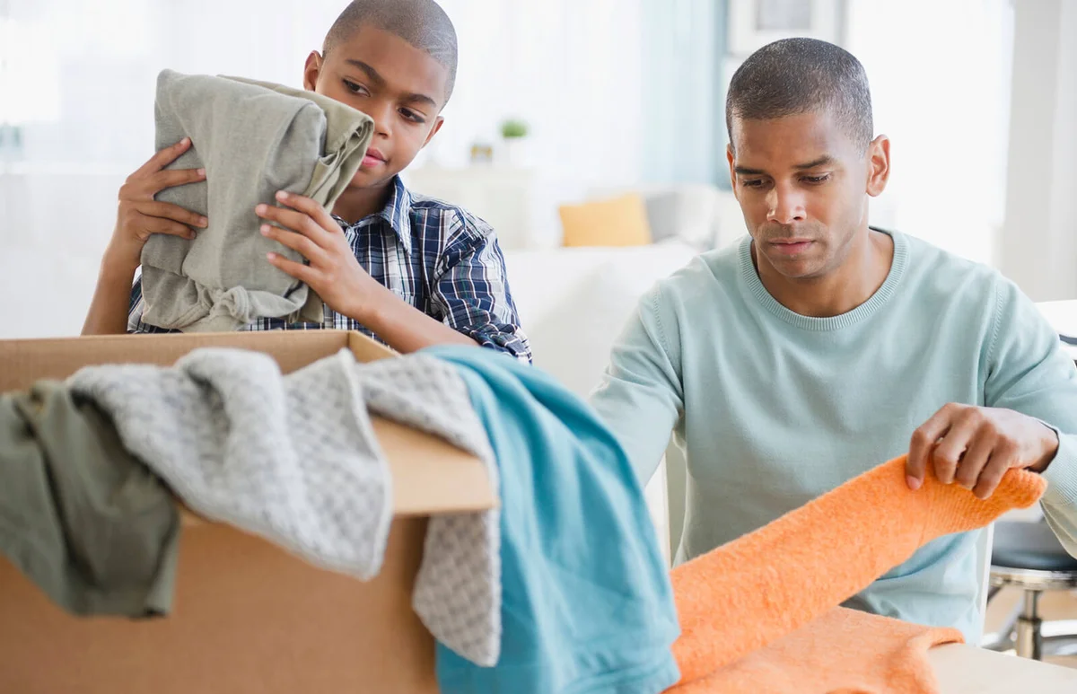 Father and son folding clothes for charity