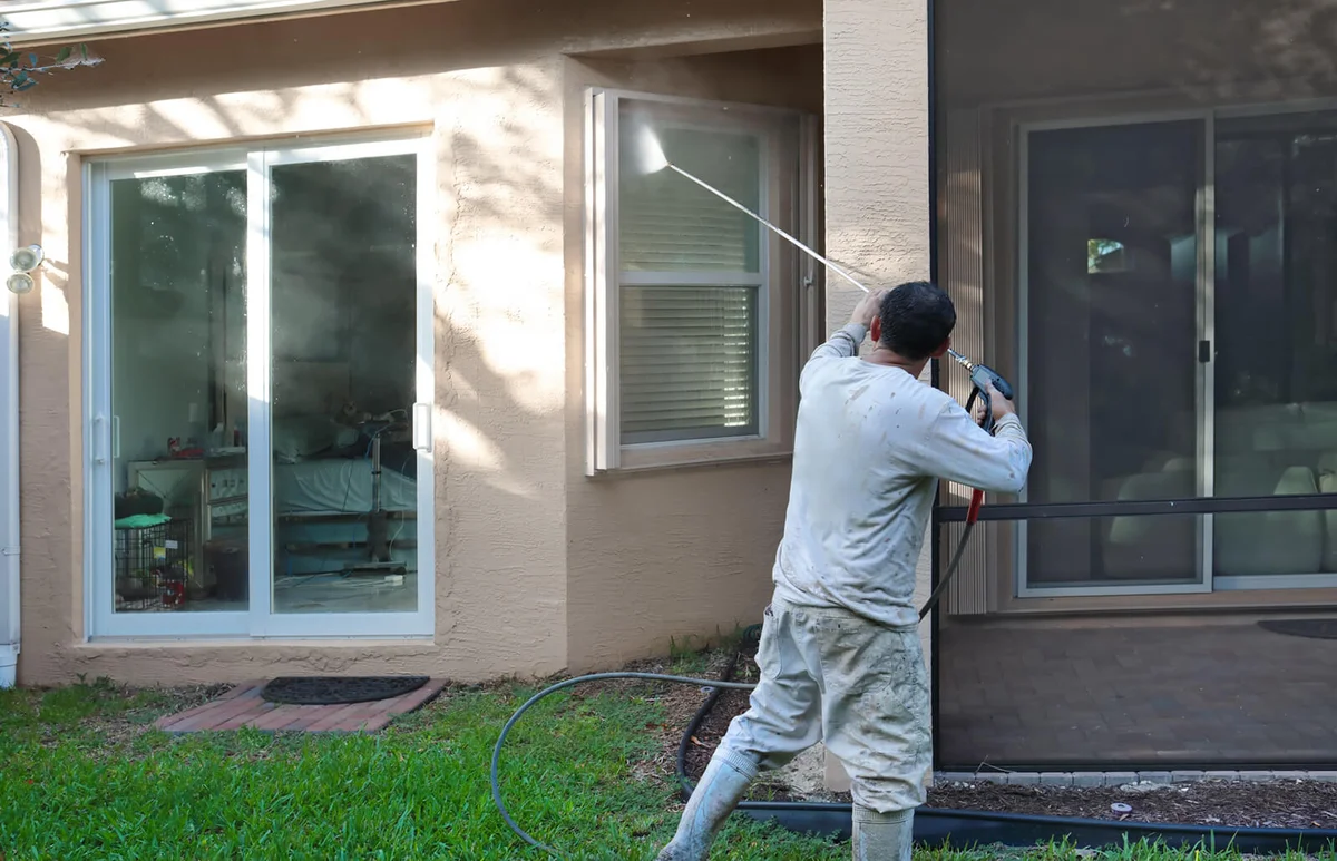 house worker power washing back of upscale home
