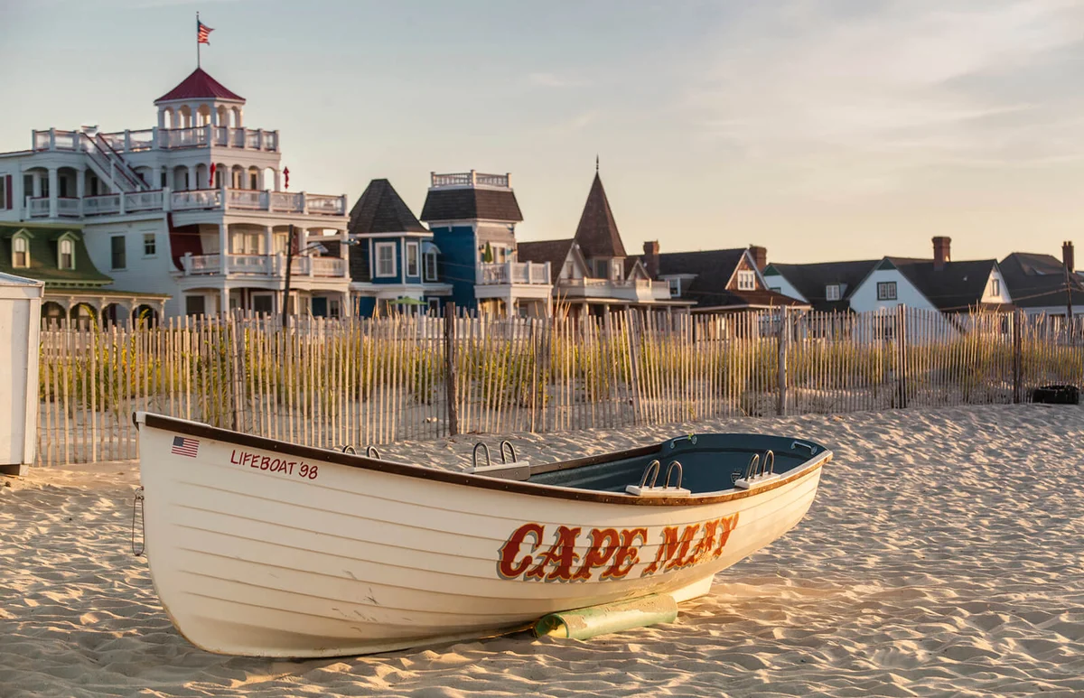 Victorian Homes and hotels line Beach Ave. in Cape May with lifesaving rescue boat on the beach