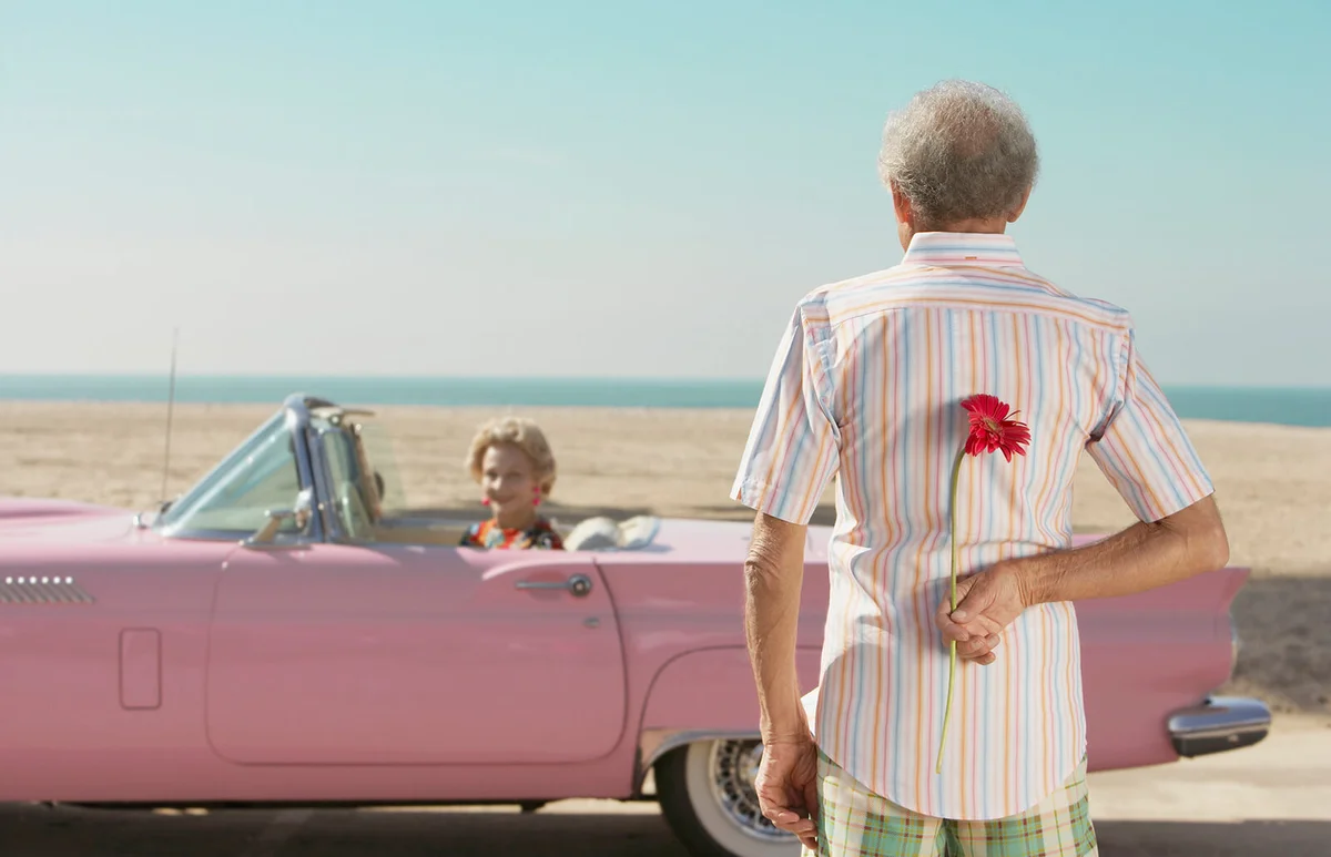 Senior man surprising wife with flower