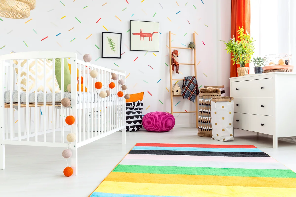 White wooden cradle with colorful balls in modern baby room
