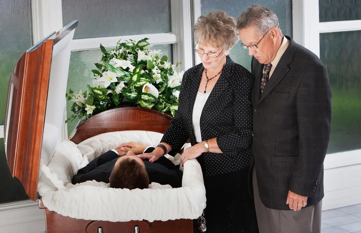 Man And Woman View The Body Of A Deceased Person In A Coffin