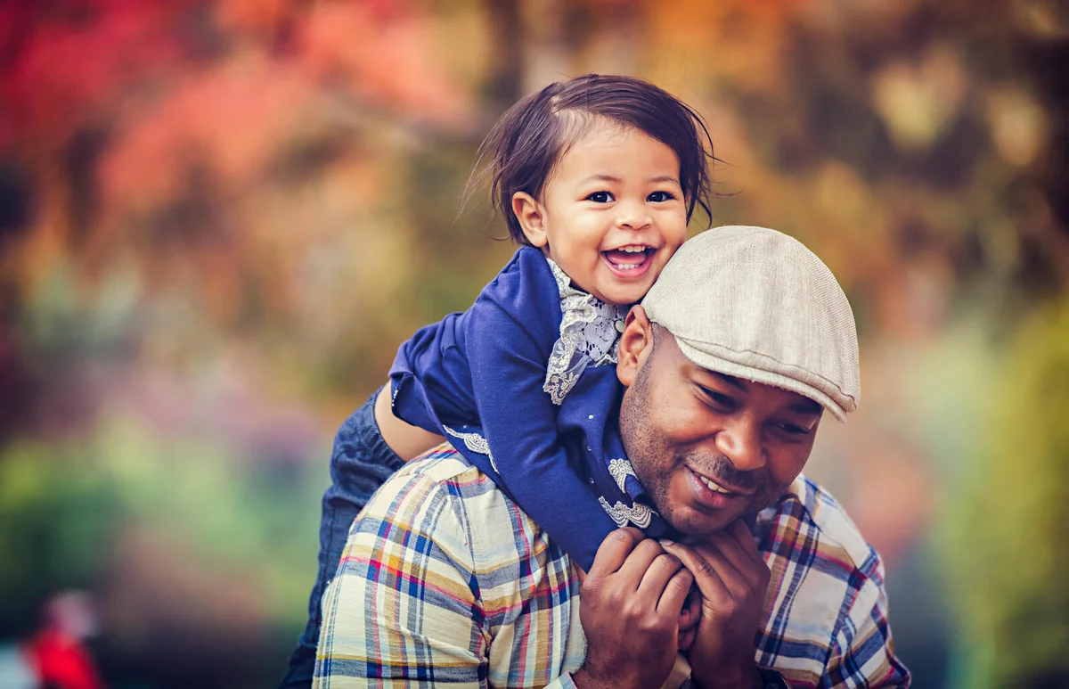 Happy Father Piggybacking Daughter During Autumn