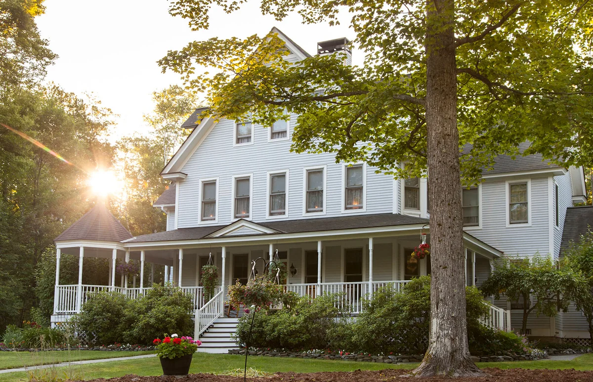Victorian home with lawn and large front porch in summer at sunset