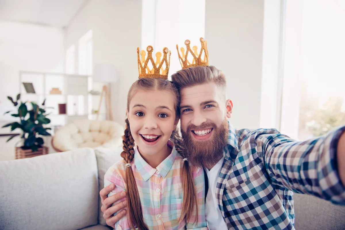Cute kid and stylish daddy wearing crowns while taking a selfie
