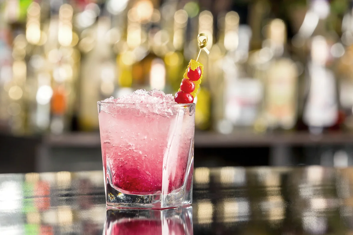 Glass of shirley temple cocktail decorated with cherry and frappe