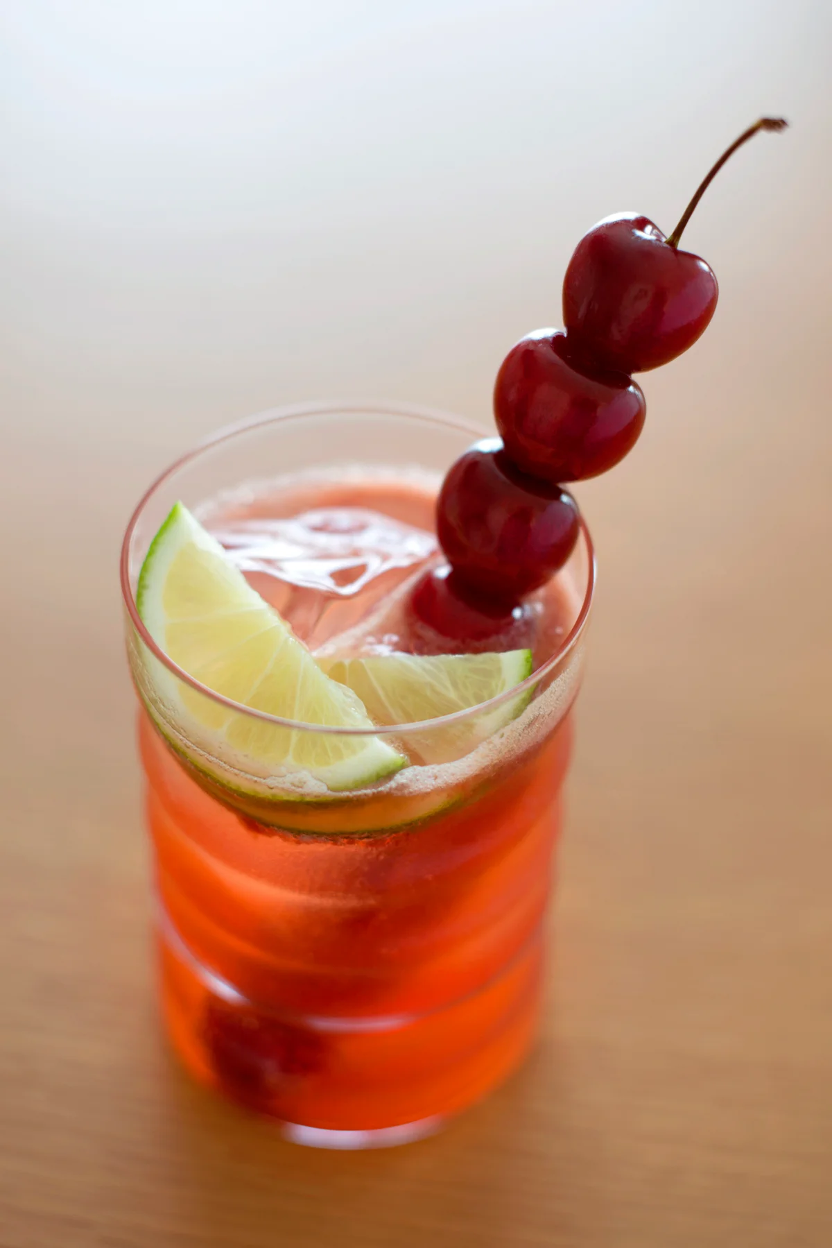 Shirley temple with fresh cherries on a long stick and two half slices of lime