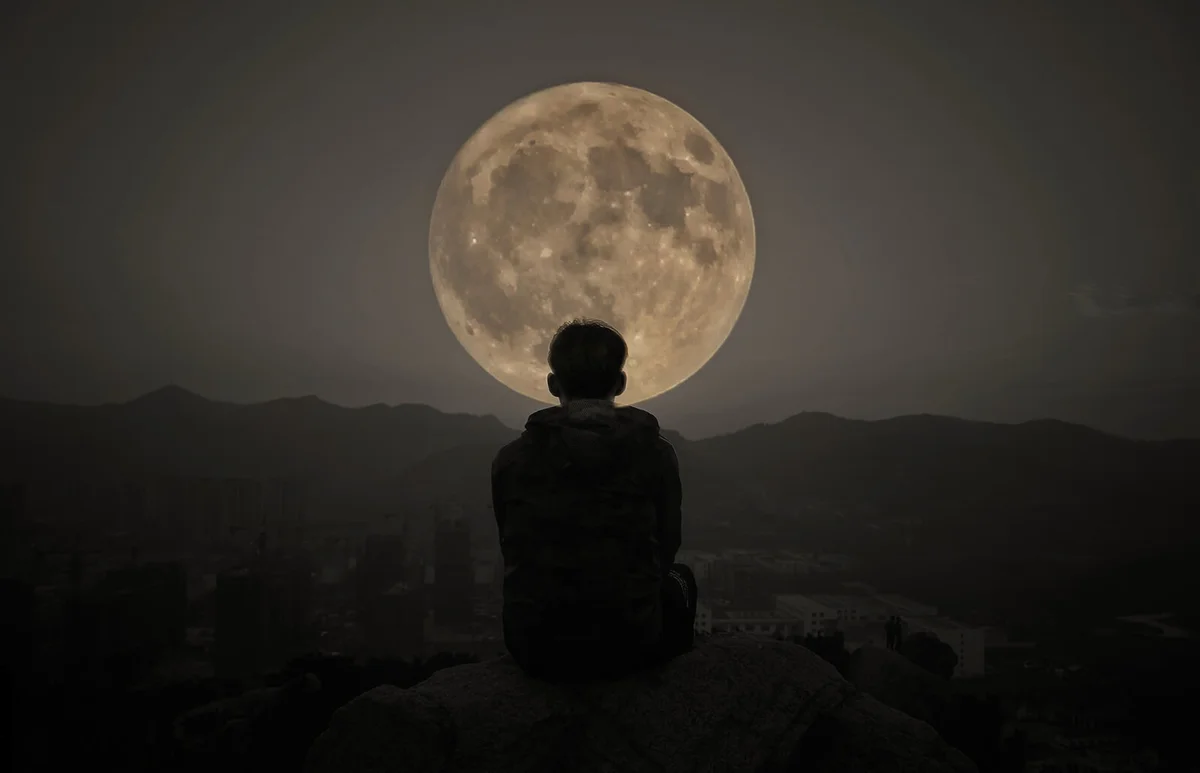 Man Sitting Against Moon At Night