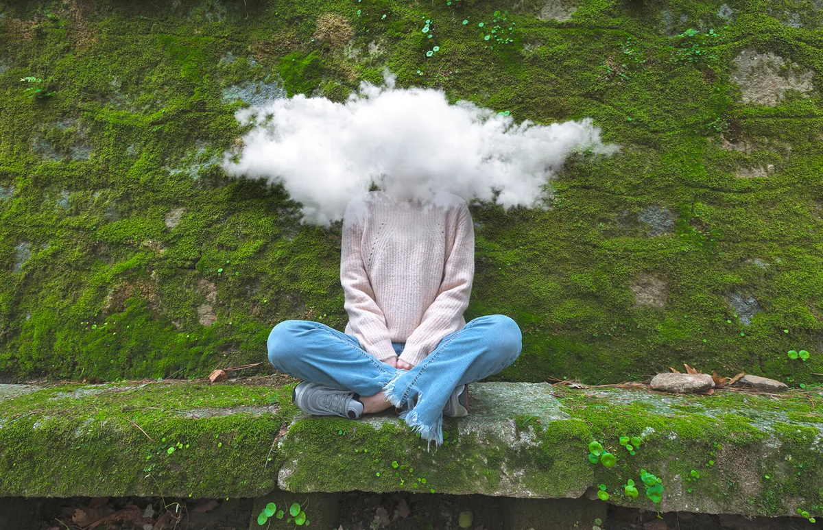Young and timid woman with head in the cloud sitting on bench