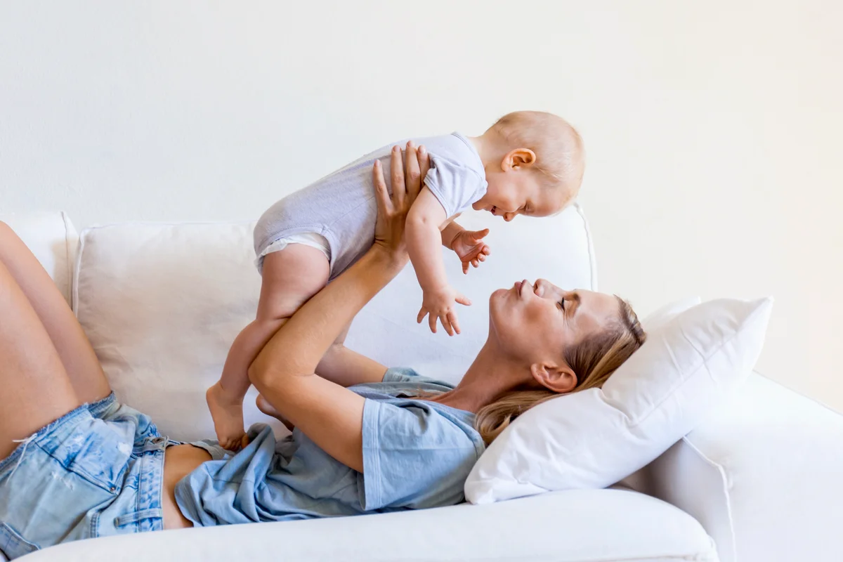 Mother lying on couch holding her baby girl