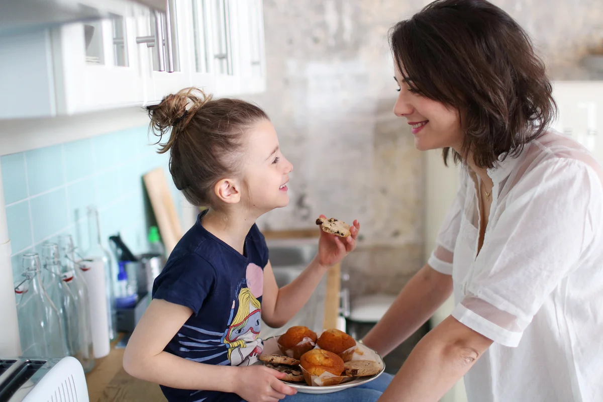 A girl and her mum in the kitchen eating cookies