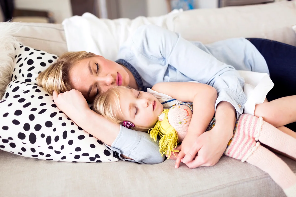 Mother and daughter sleeping on sofa