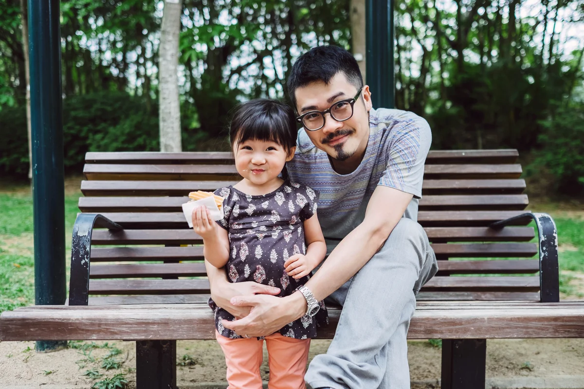 Dad and little girl smiling at the camera in park