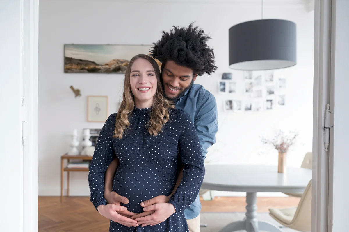 Smiling pregnant couple in living room