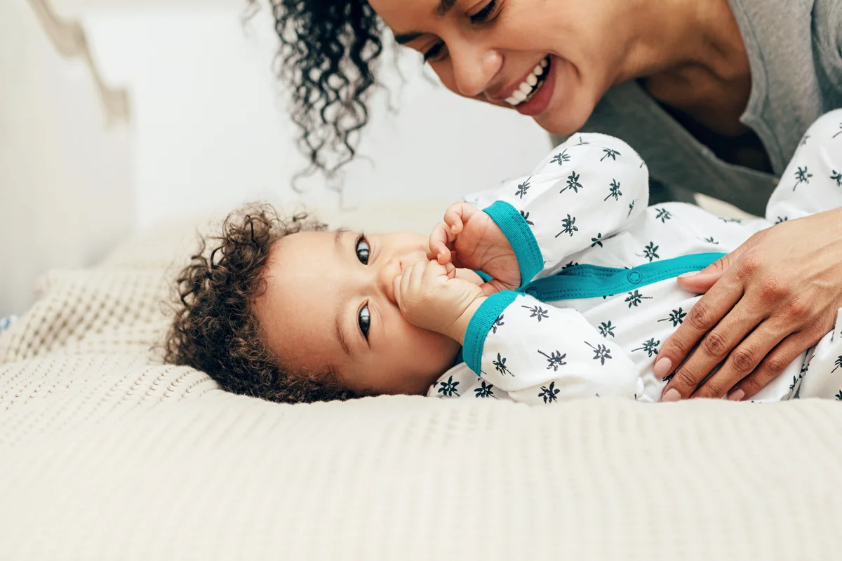 Mother Playing With Son On Bed At Home