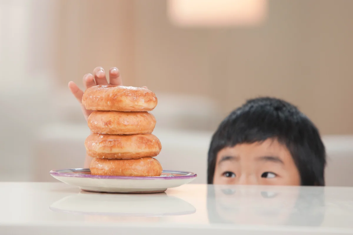 Little boy taking donut from stack
