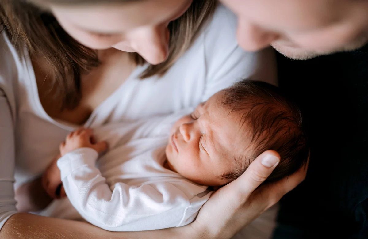Mother and father holding a newborn baby son at home