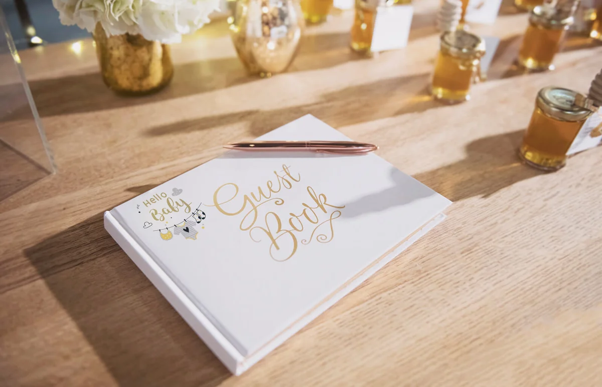 White guestbook with rose gold pen on a wooden table