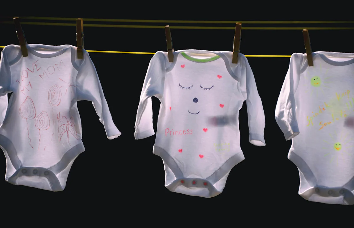 Baby clothes hanging on a washing line with clothes pins