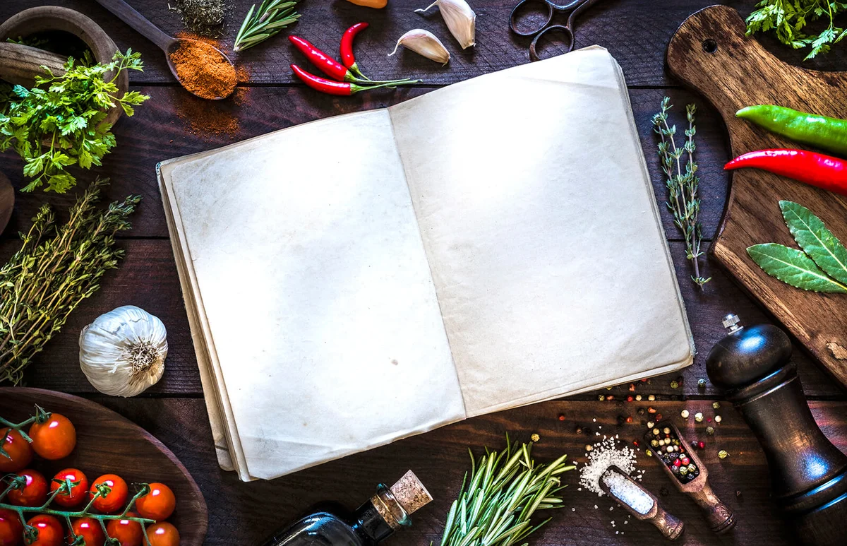 Vintage cookbook with spices and herbs on rustic wooden background