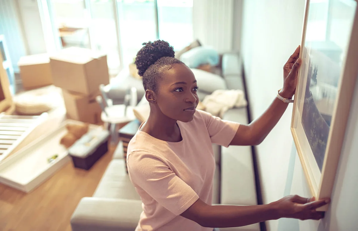 Young girl putting up a painting in her new home