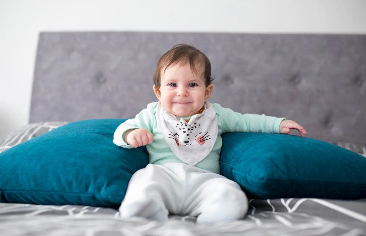 Newborn baby girl sitting with support pillows