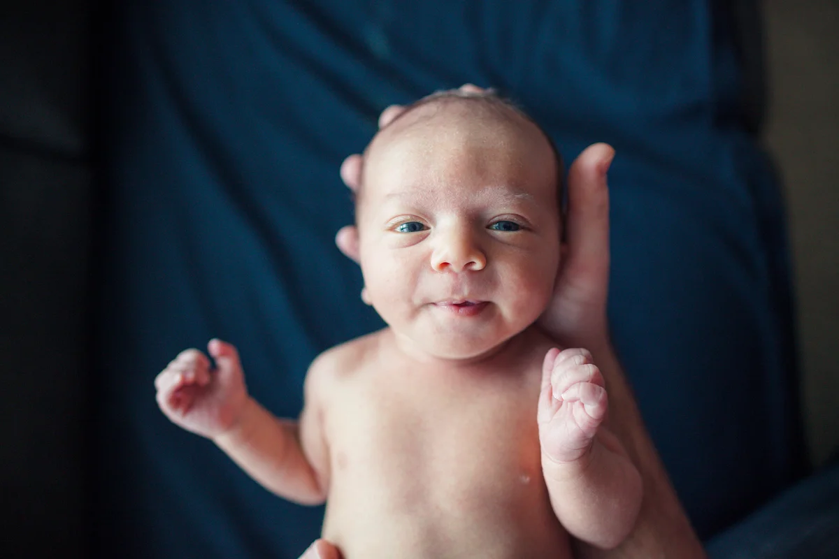 Overhead portrait of newborn baby boy held by father