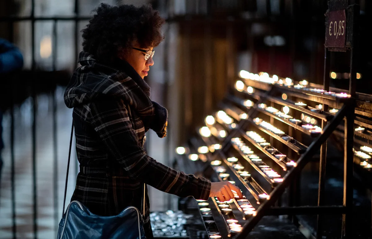 Young woman lighting a candle in the church on holiday