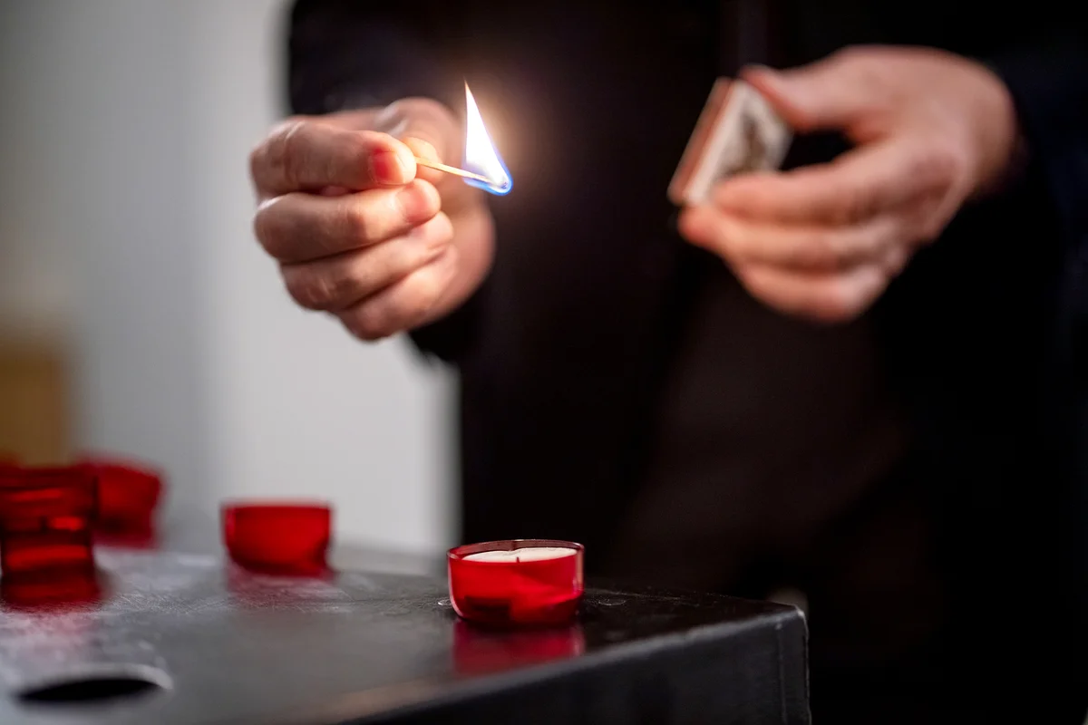 Man igniting candles with matchsticks lighting up a candle