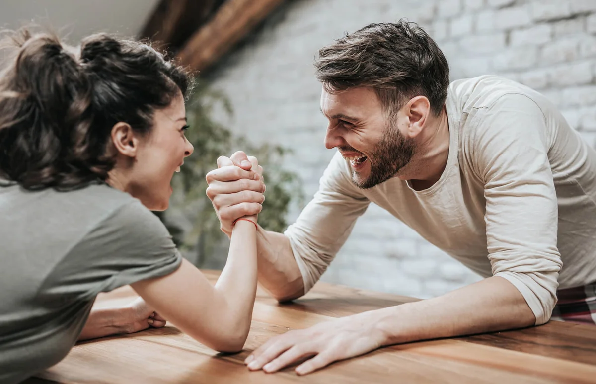 couple having fun while arm wrestling at home