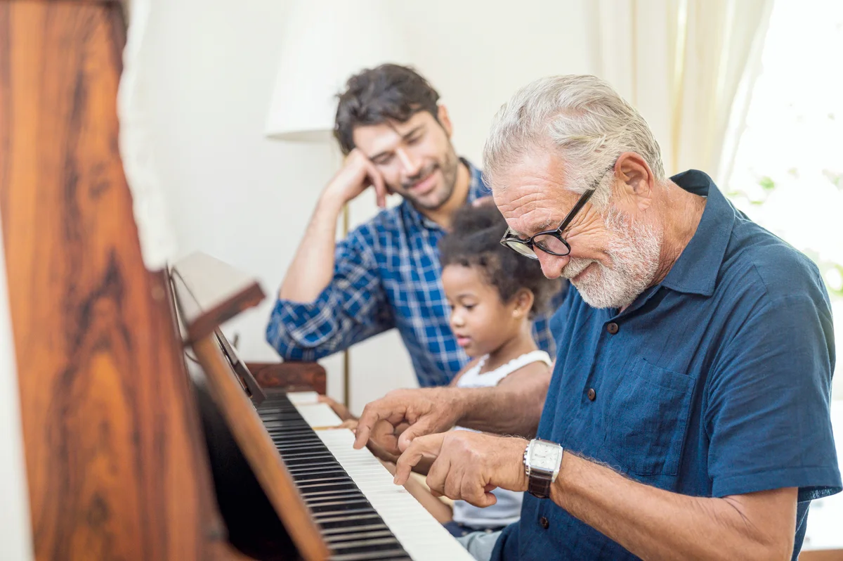Grandfather playing piano with his granddaughter and son