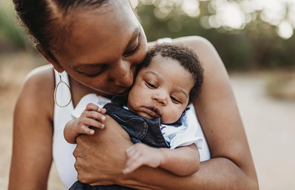 young mother holdiing infant daughter outside