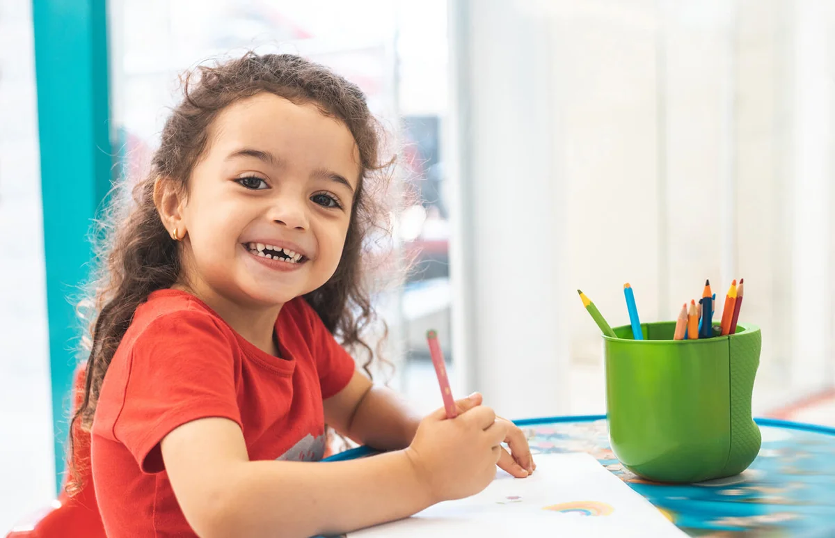 Little girl drawing with colorful pencils