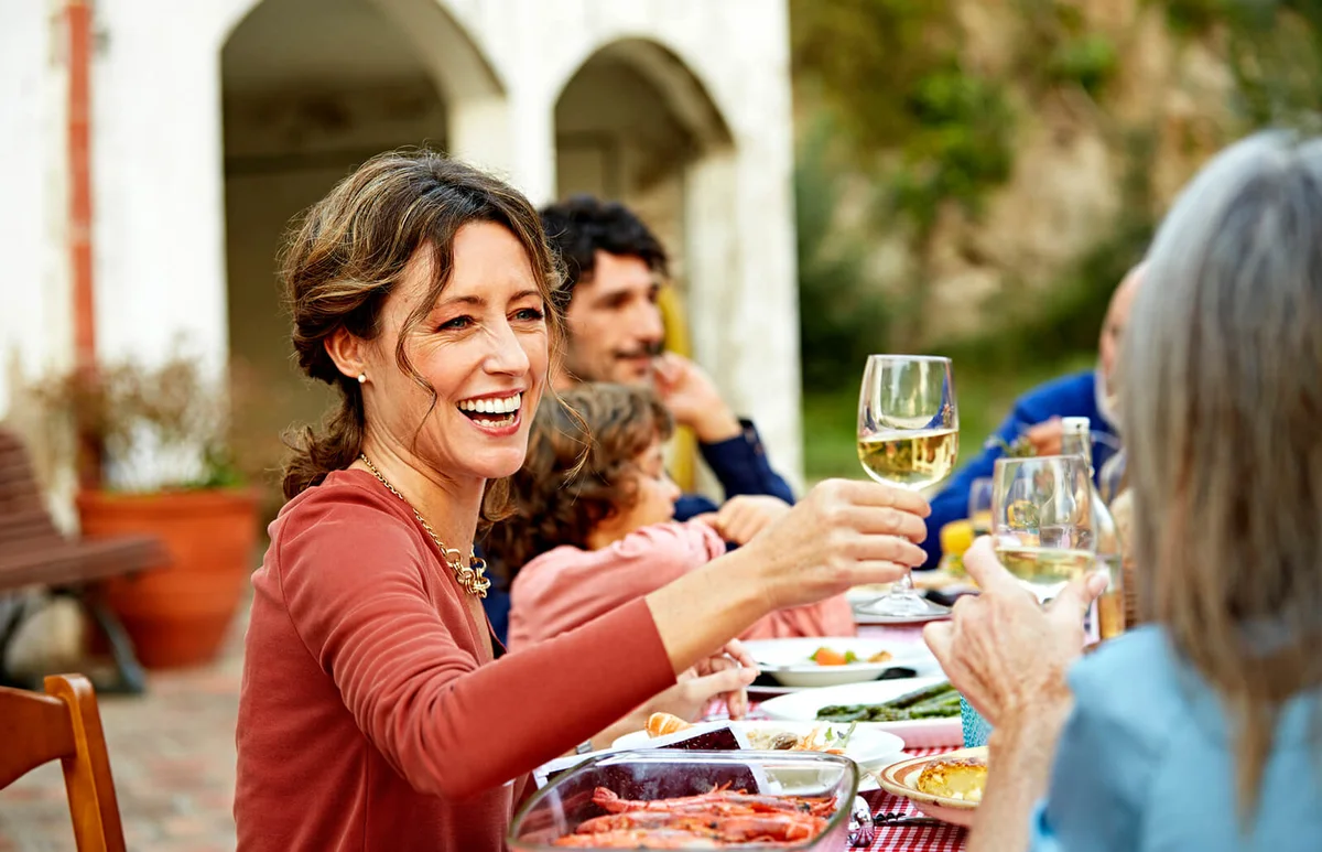 Woman enjoying wine while having meal with family