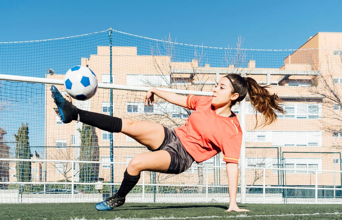 Young girl playing football in grass field