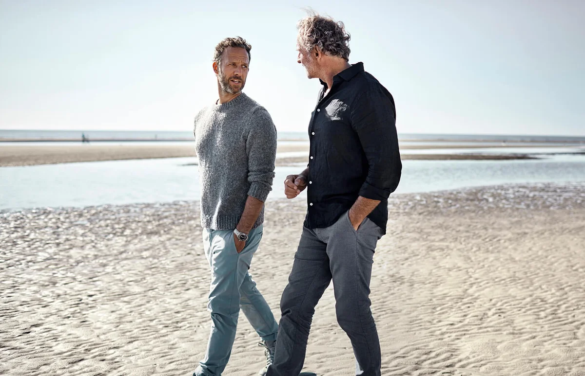Two men walking and talking on the beach