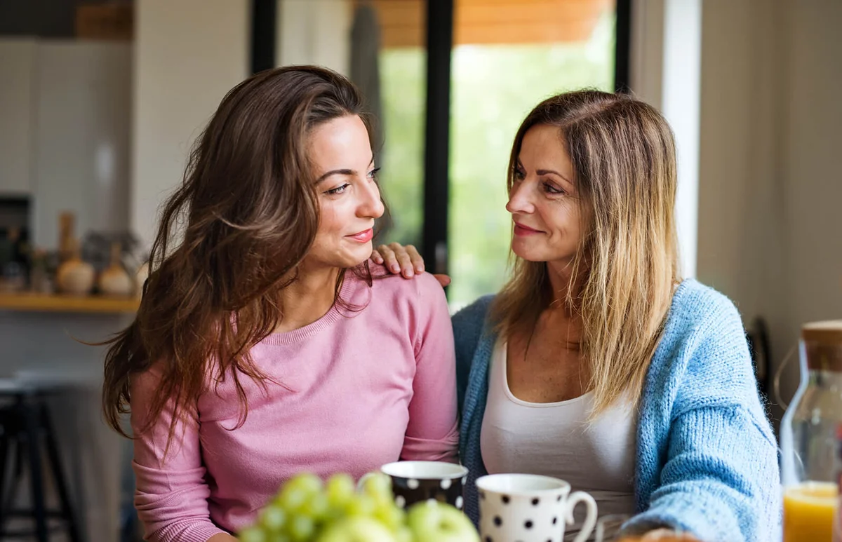 mature mother with adult daughter sitting at home