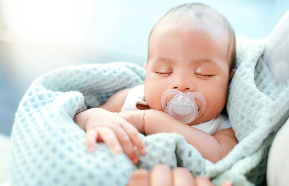 adorable baby boy sleeping in his mother's arms