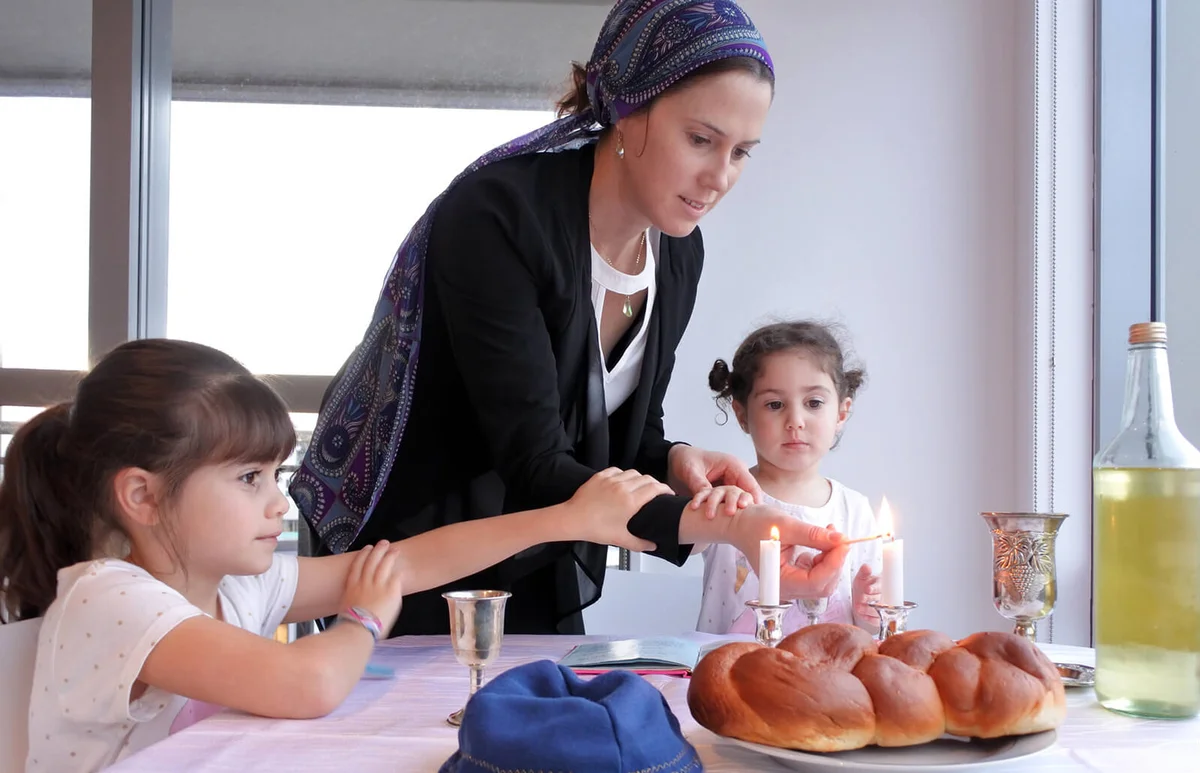 Jewish mother and daughters light Sabbath candles
