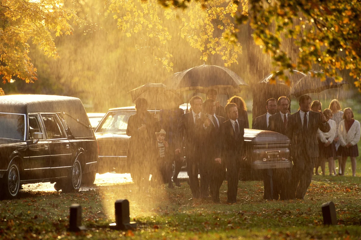 Funeral procession in cemetery during rainstorm