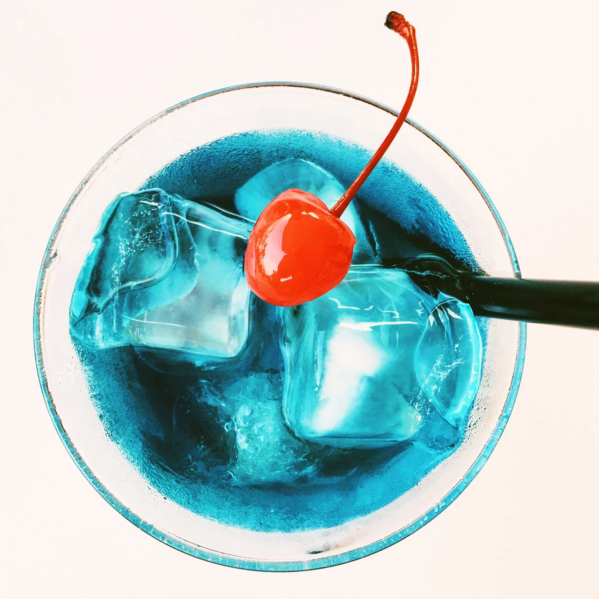 Cherry In Blue Cocktail Against White Background