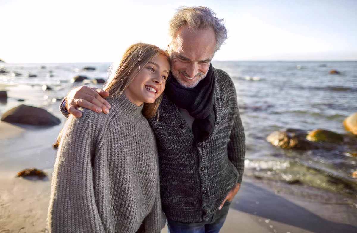 Father and happy daughter strolling on the beach
