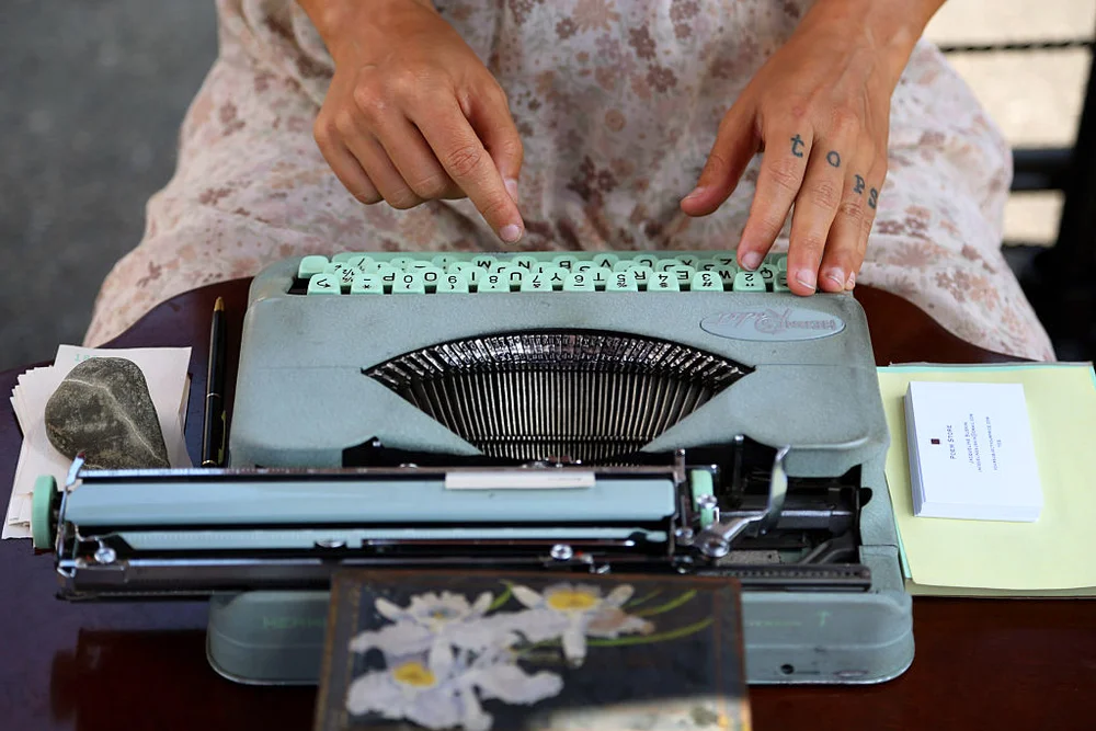Writing in a blue Hermes Typewriter